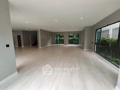 Spacious open-plan living room with large windows and garden view, perfect for modern family living.