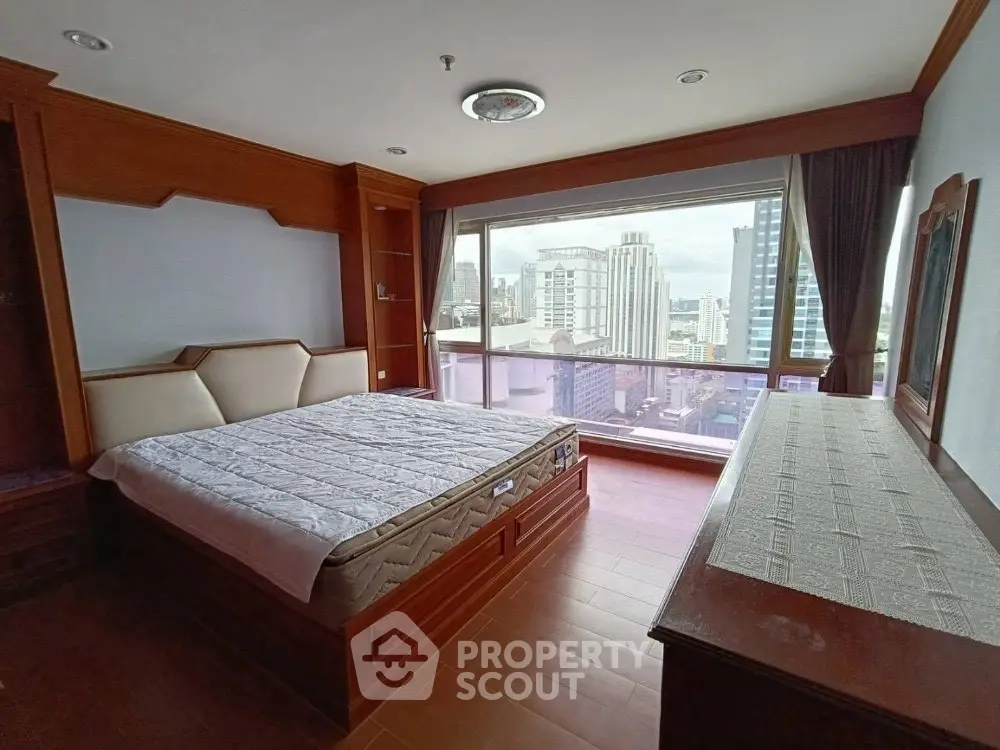 Spacious bedroom with large window offering stunning city views in a modern apartment.