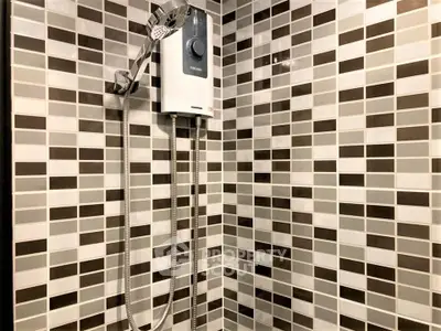 Modern bathroom shower with stylish tile design and electric water heater.