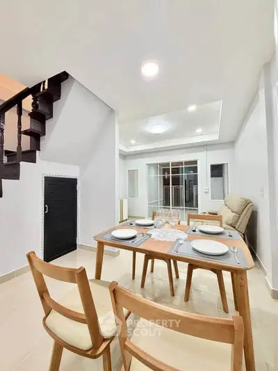 Modern dining area with elegant staircase and cozy seating in a stylish home interior.