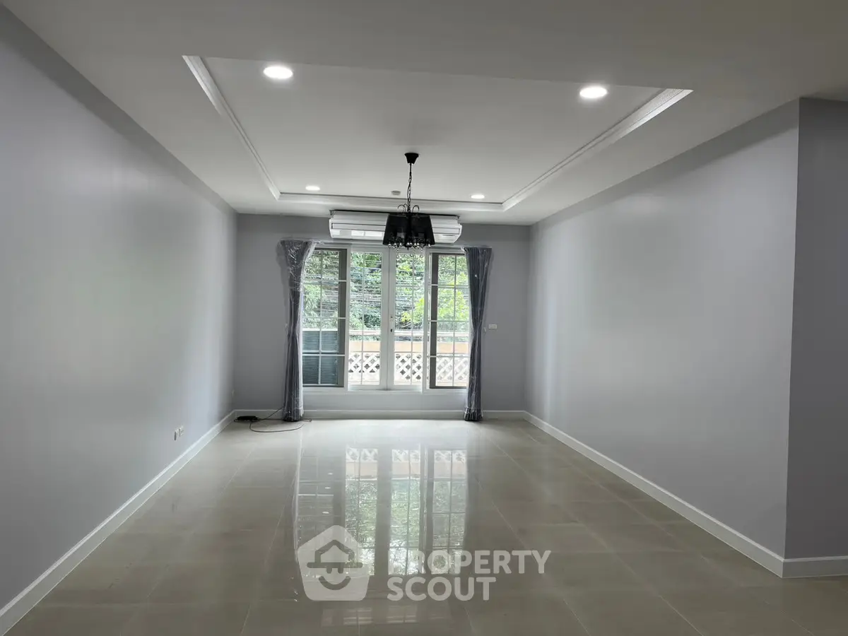 Spacious empty living room with large windows and modern lighting
