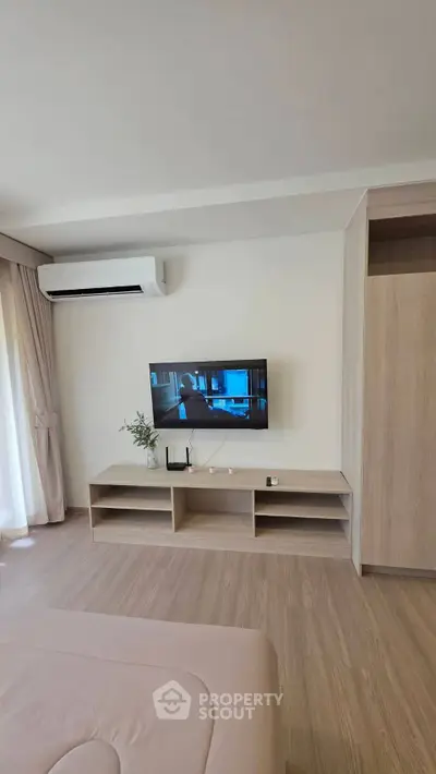 Modern bedroom with TV and air conditioning, featuring minimalist wooden furniture and soft lighting.
