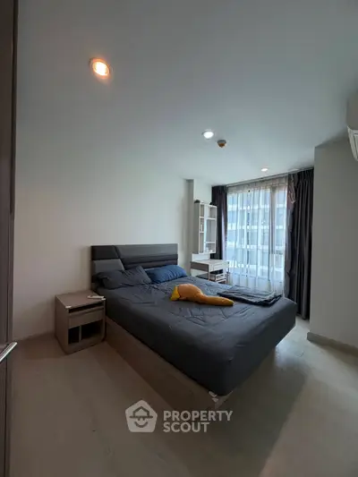 Modern bedroom with large window and stylish furnishings in a contemporary apartment.