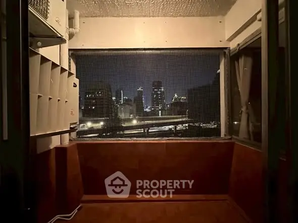 Cozy balcony with stunning city skyline view at night, perfect for relaxation.