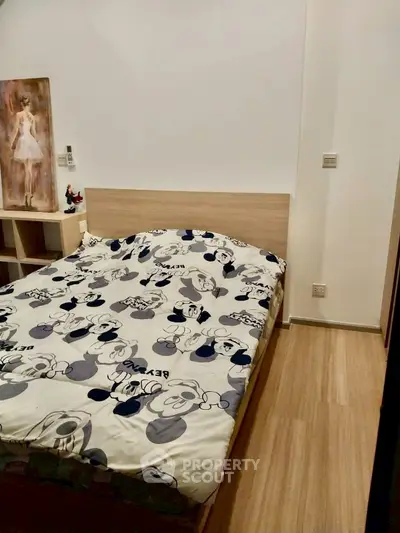 Cozy bedroom with wooden flooring and stylish bedding in modern apartment.