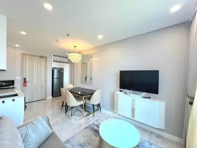 Modern living room with elegant decor, featuring a wall-mounted TV, dining area, and stylish lighting.