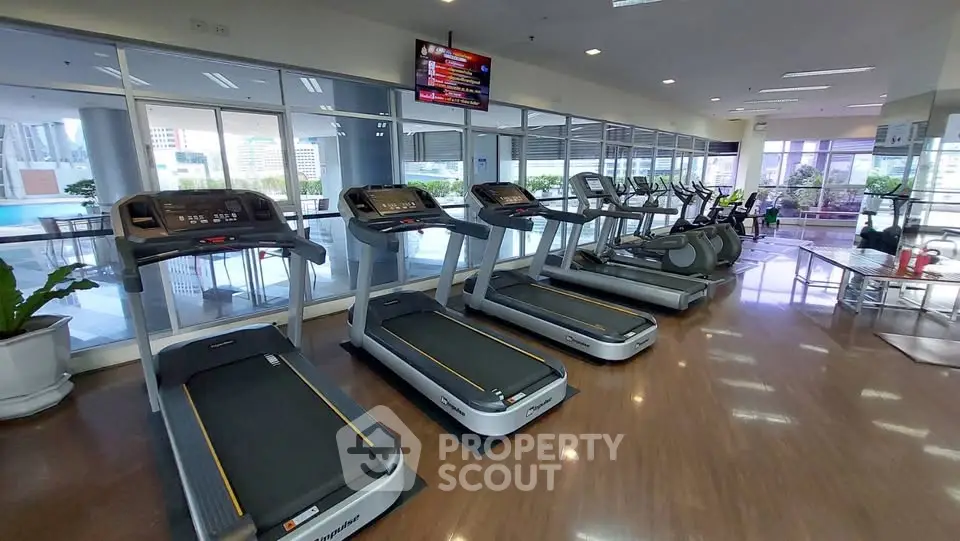Spacious gym with modern treadmills and city view, perfect for fitness enthusiasts.