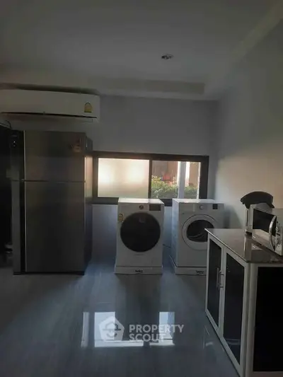 Modern laundry room with washing machine, dryer, and fridge in sleek design.