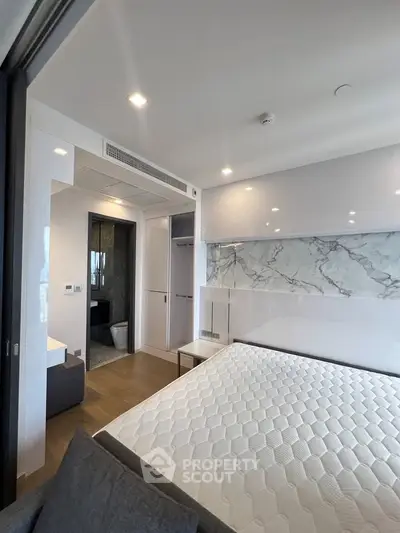 Modern bedroom with marble accent wall and ensuite bathroom in luxury apartment