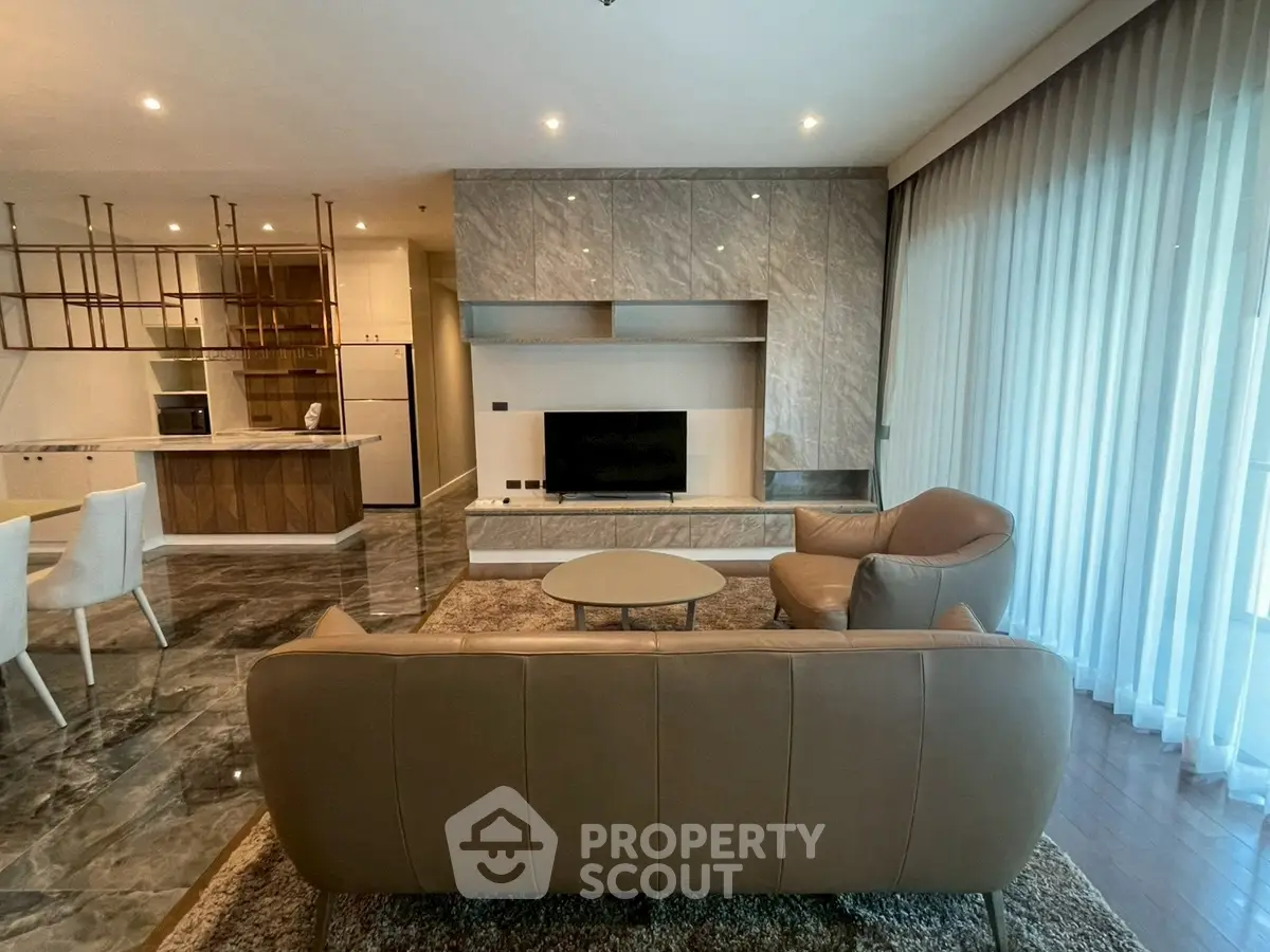 Luxurious modern living room with elegant marble accents and open kitchen layout.