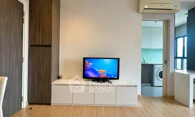 Modern living room with TV and view into kitchen with washing machine