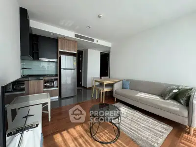 Modern living room with open kitchen, stylish furniture, and natural light.