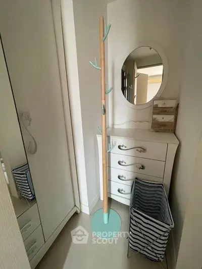Charming small bedroom corner with mirror, dresser, and coat rack, perfect for cozy living spaces.