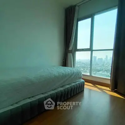 Bright bedroom with large window offering stunning city view, featuring a cozy bed and elegant curtains.