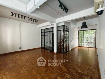 Spacious modern living room with parquet flooring and glass partition, ideal for stylish urban living.