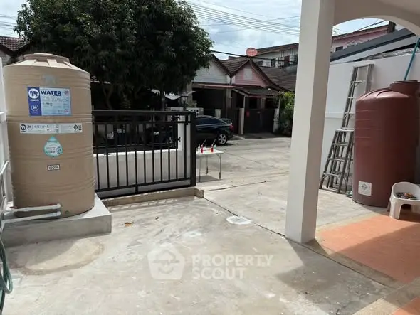 Spacious outdoor area with water tanks and driveway in a residential property.