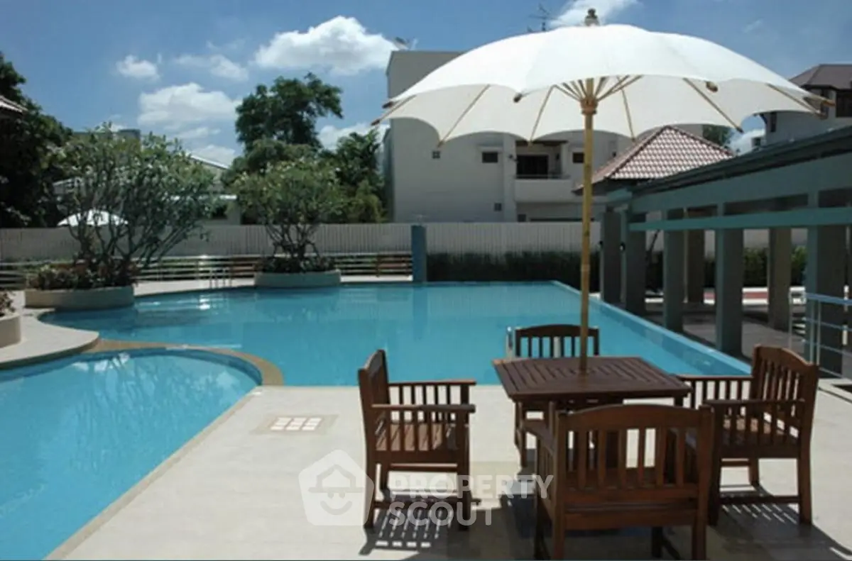 Luxurious outdoor pool area with elegant seating and umbrella, perfect for relaxation and entertainment.