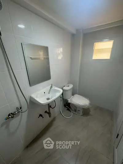 Modern bathroom with sleek white tiles and compact fixtures, ideal for urban living.