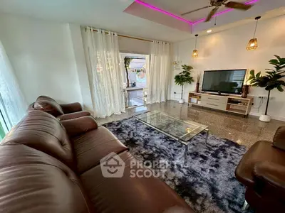 Spacious living room with leather sofas, modern decor, and large windows for natural light.