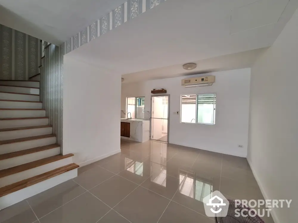 Spacious open-plan living area with modern staircase and tiled flooring