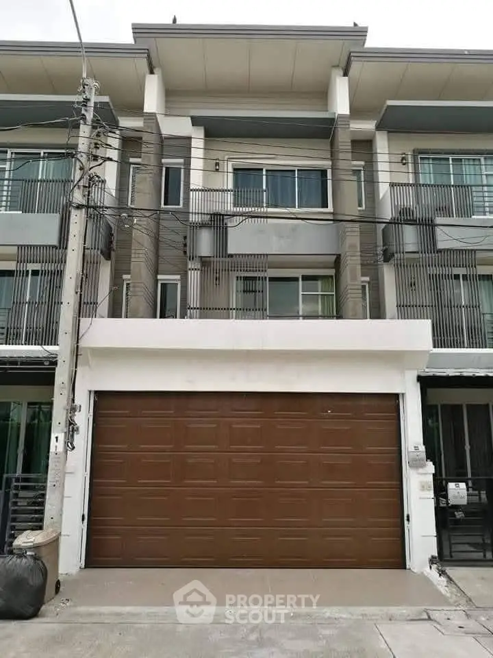 Modern townhouse exterior with large garage door and balcony