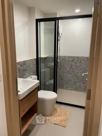 Modern bathroom with sleek design, featuring a glass-enclosed shower and stylish fixtures.