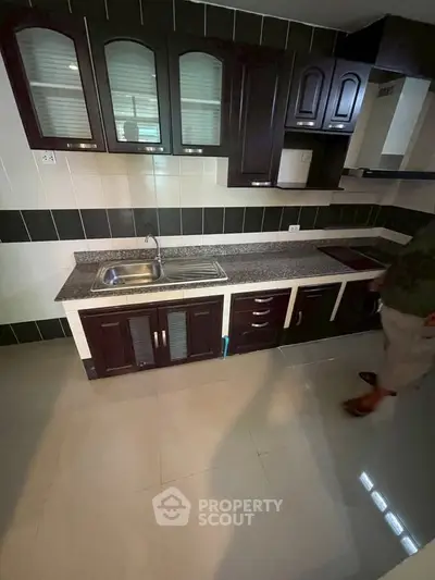 Modern kitchen with dark wood cabinets and sleek countertops in a stylish apartment.
