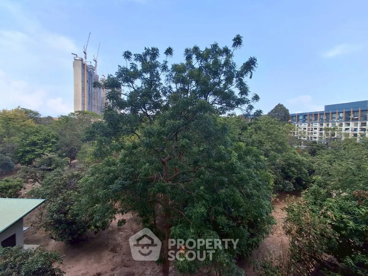 Lush green garden view with construction in the background, ideal for nature lovers seeking urban living.