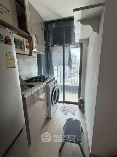 Compact kitchen with washing machine and city view from balcony