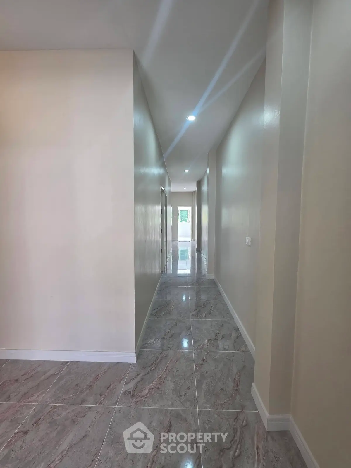 Spacious hallway with glossy marble flooring and modern lighting in a contemporary home.