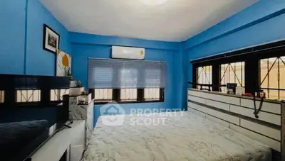 Spacious bedroom with blue walls and large windows, featuring modern decor and ample natural light.
