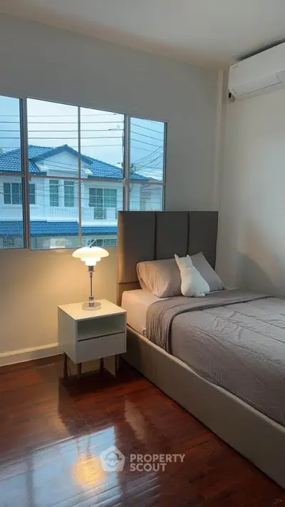 Cozy bedroom with modern decor and large window overlooking neighborhood view