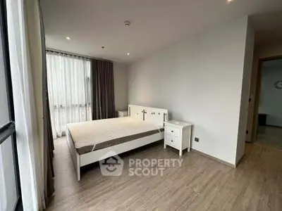 Spacious modern bedroom with large window and minimalist decor in a stylish apartment.