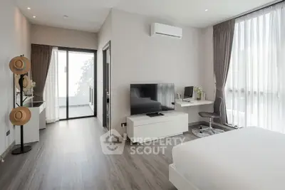 Modern bedroom with sleek design, featuring a workspace and large windows for natural light.