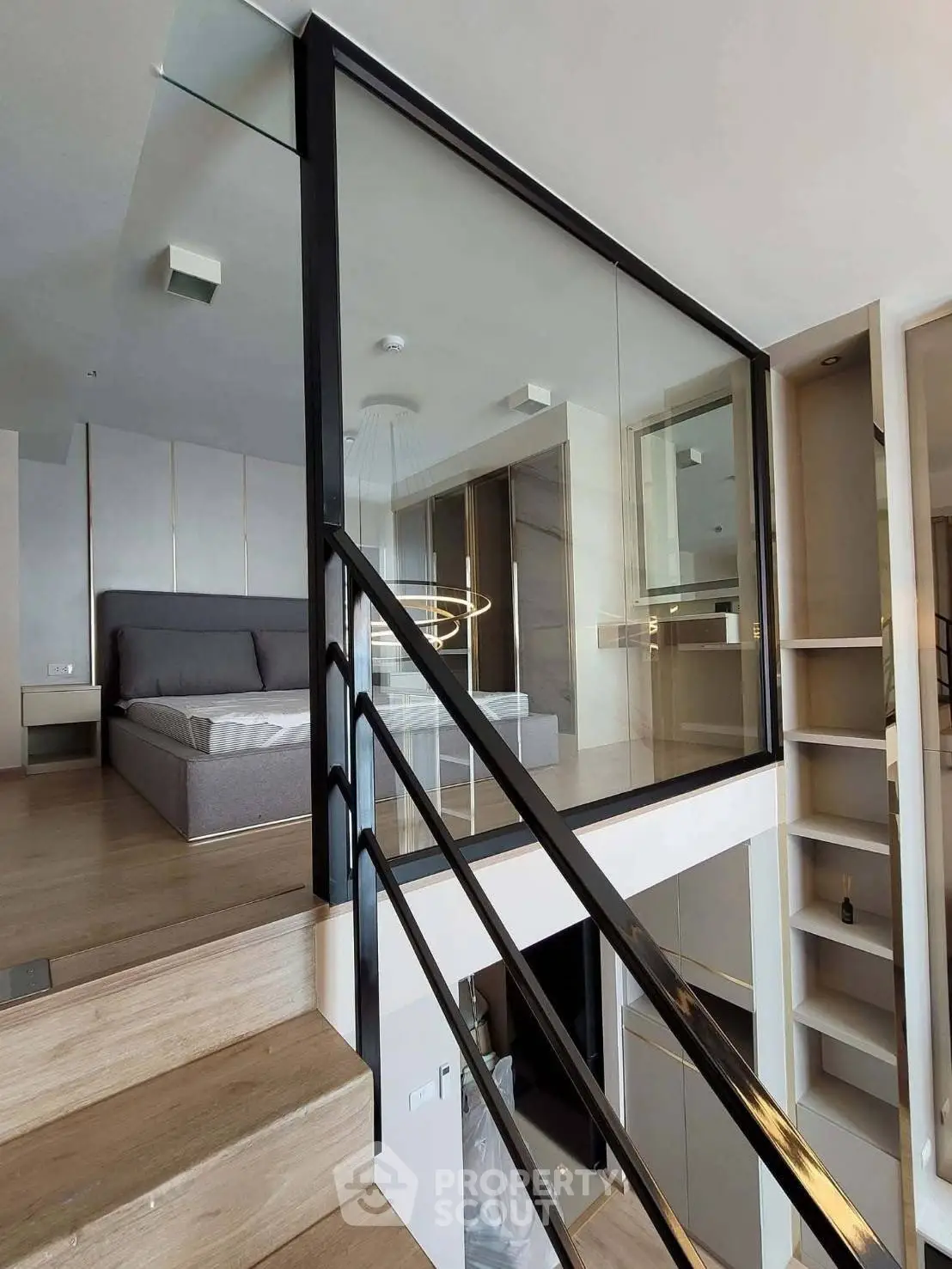 Modern duplex bedroom with glass railing and wooden flooring, featuring sleek design and ample natural light.
