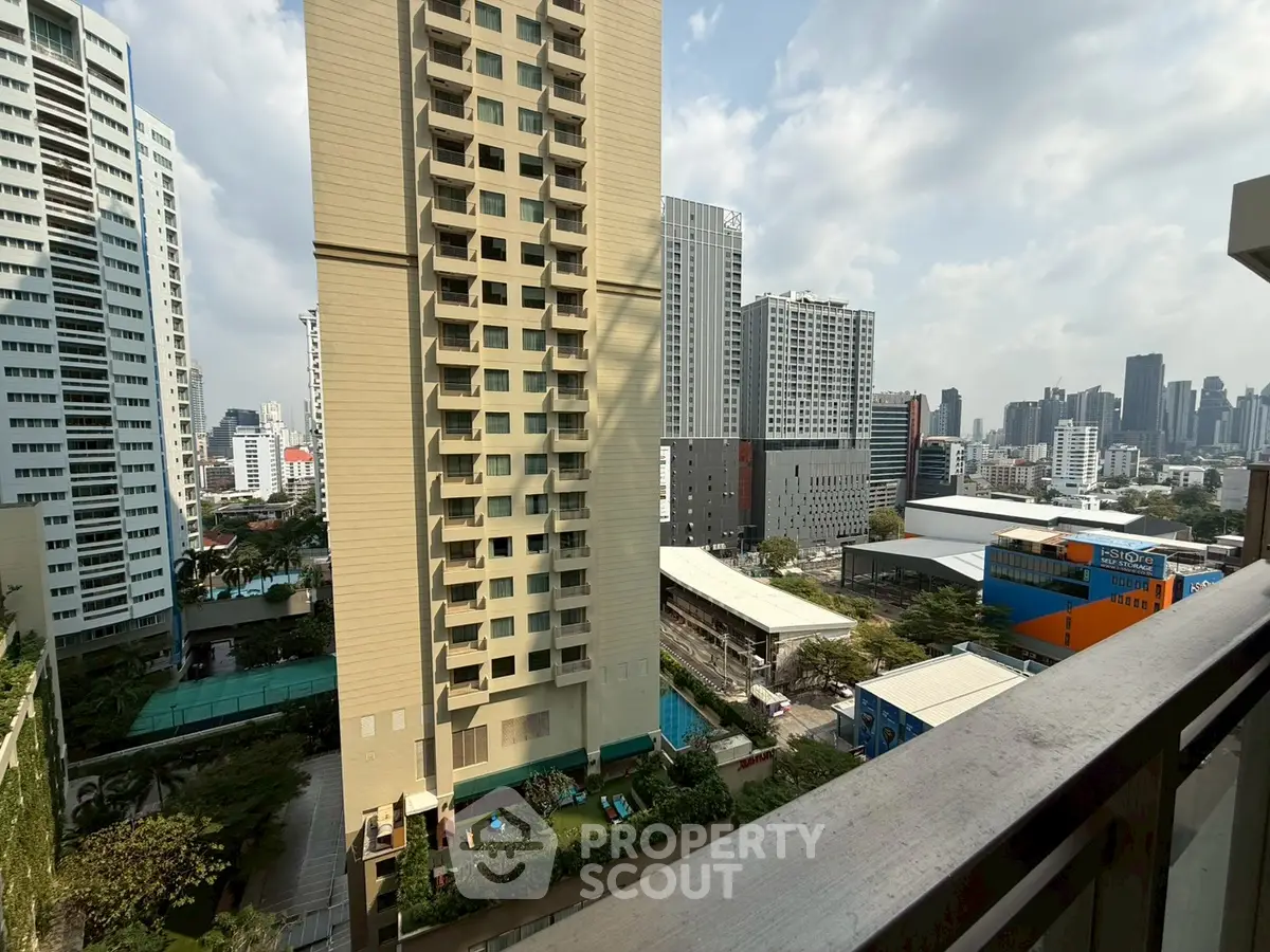 Stunning cityscape view from a high-rise balcony overlooking modern urban skyline and residential buildings.