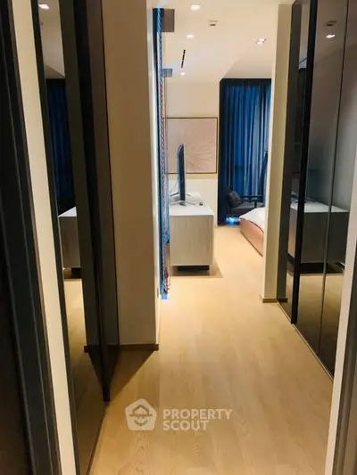 Modern bedroom with sleek design and wooden flooring, featuring a large TV and elegant decor.