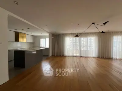 Spacious modern living room with open kitchen and large windows for natural light.