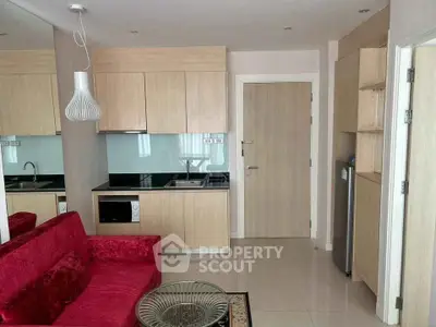 Modern compact living room with open kitchen, featuring sleek cabinetry and vibrant red sofa.