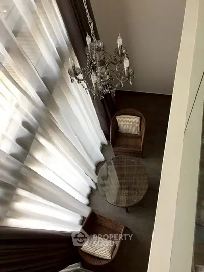 Elegant high-ceiling living area with chandelier and cozy seating