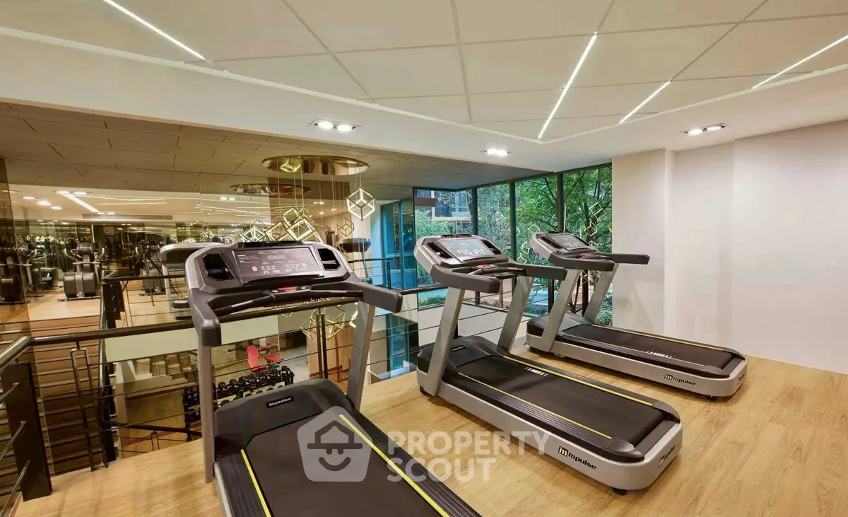 Modern gym with treadmills and large windows in luxury real estate property.
