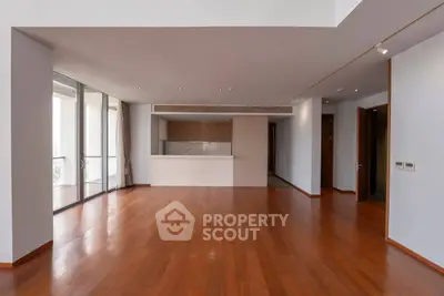 Spacious open-plan living room with hardwood floors and modern kitchen in luxury apartment.