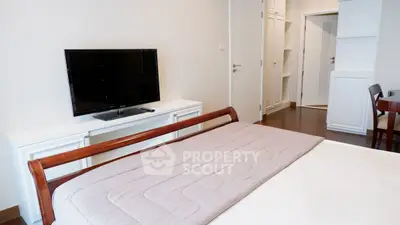 Spacious bedroom with modern TV and elegant wooden furniture