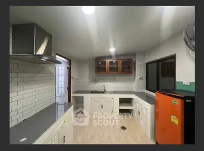 Modern kitchen with sleek countertops and vibrant orange fridge