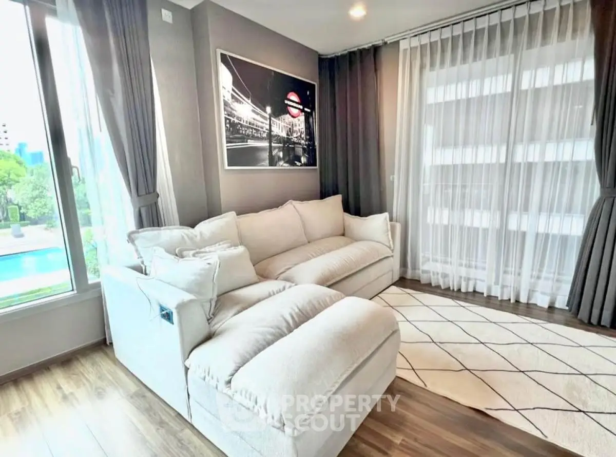 Spacious living room with modern decor and large windows offering pool view