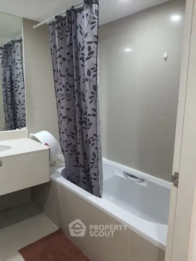 Modern bathroom with sleek design featuring a bathtub and stylish shower curtain.