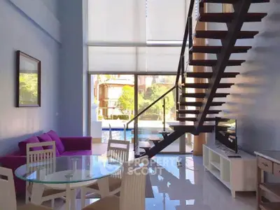 Modern living room with glass table, purple sofa, and stylish staircase