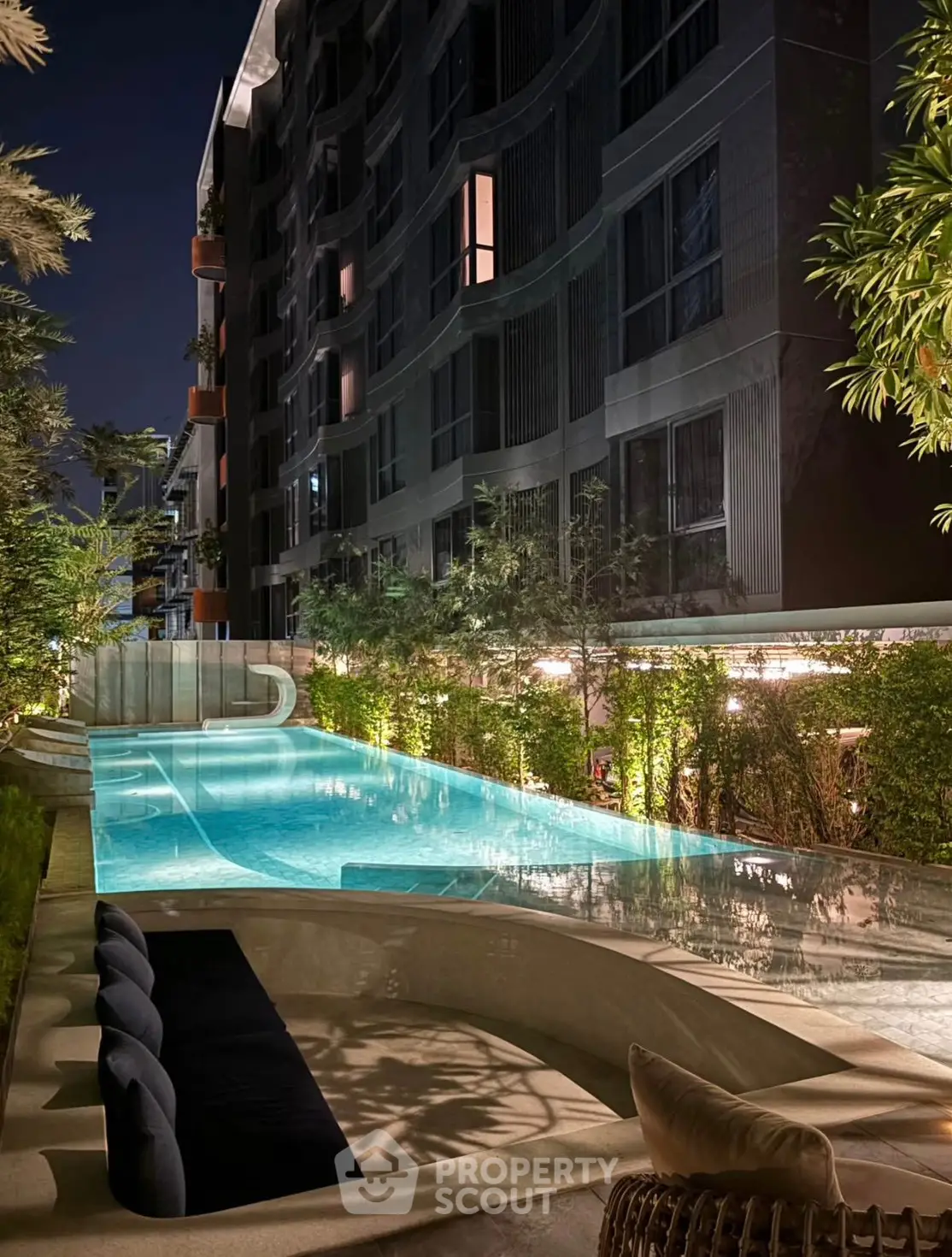 Luxurious night view of modern apartment building with illuminated poolside ambiance.