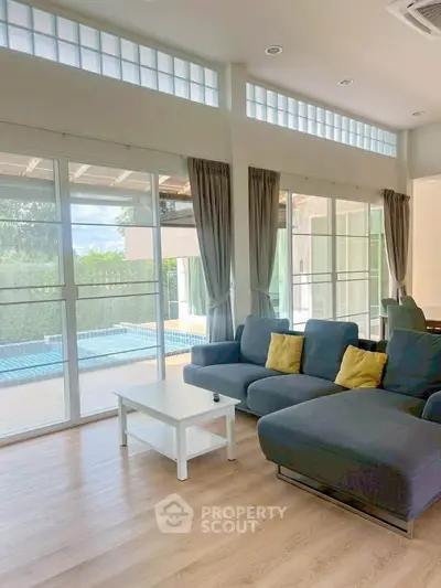Spacious living room with pool view, featuring modern furniture and large windows for natural light.