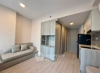 Modern apartment interior with sleek kitchen and cozy living area, featuring light wood finishes and minimalist design.
